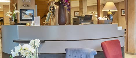 A reception area with a counter, seating, and a coffee table with books and flowers.