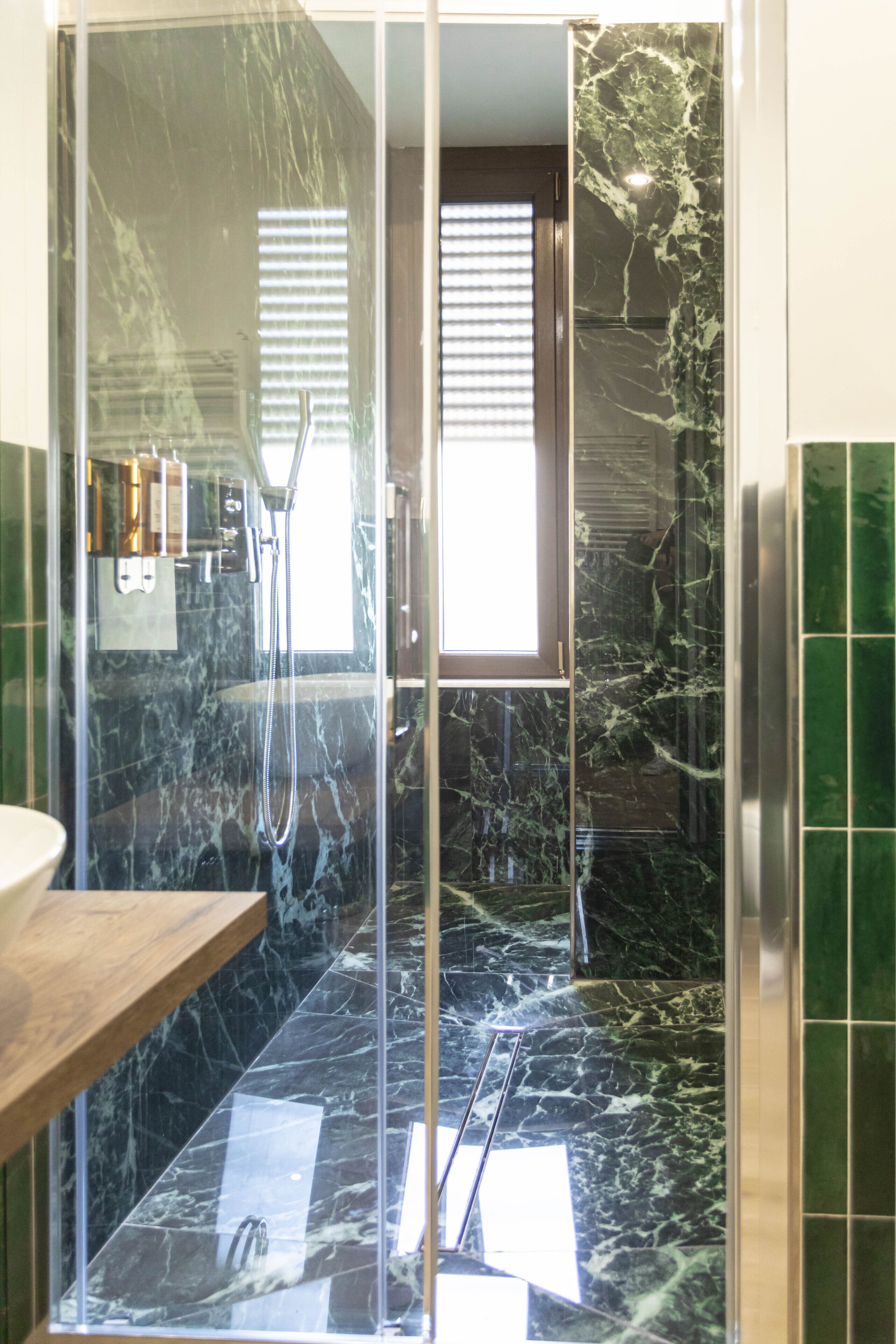 A modern bathroom with a glass-enclosed shower, marble flooring, and a wooden vanity.