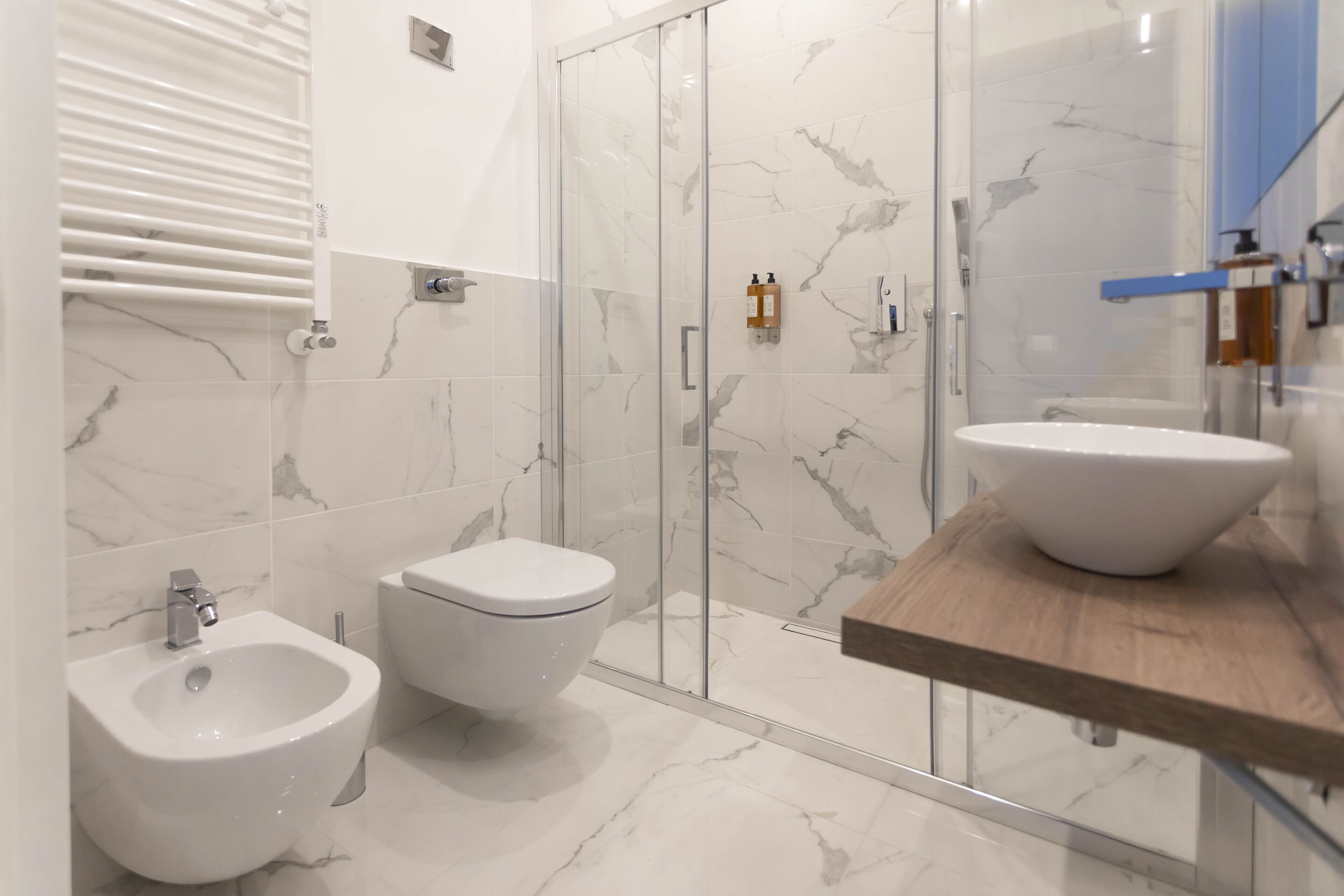 Une salle de bain moderne équipée d’un bidet, de toilettes et d’une douche à parois de verre.