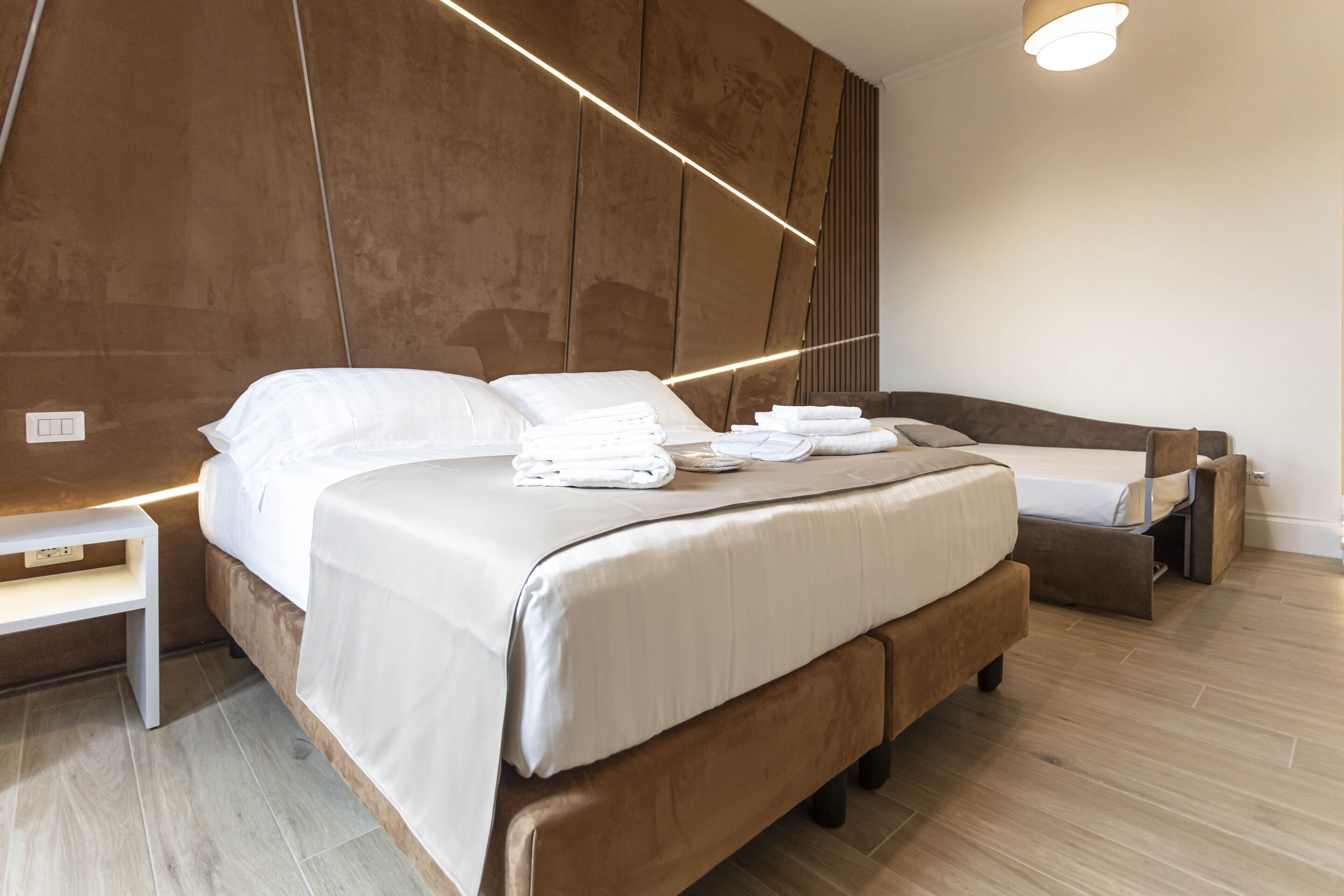 A modern bedroom with a large bed, bedside tables, and a built-in bench.