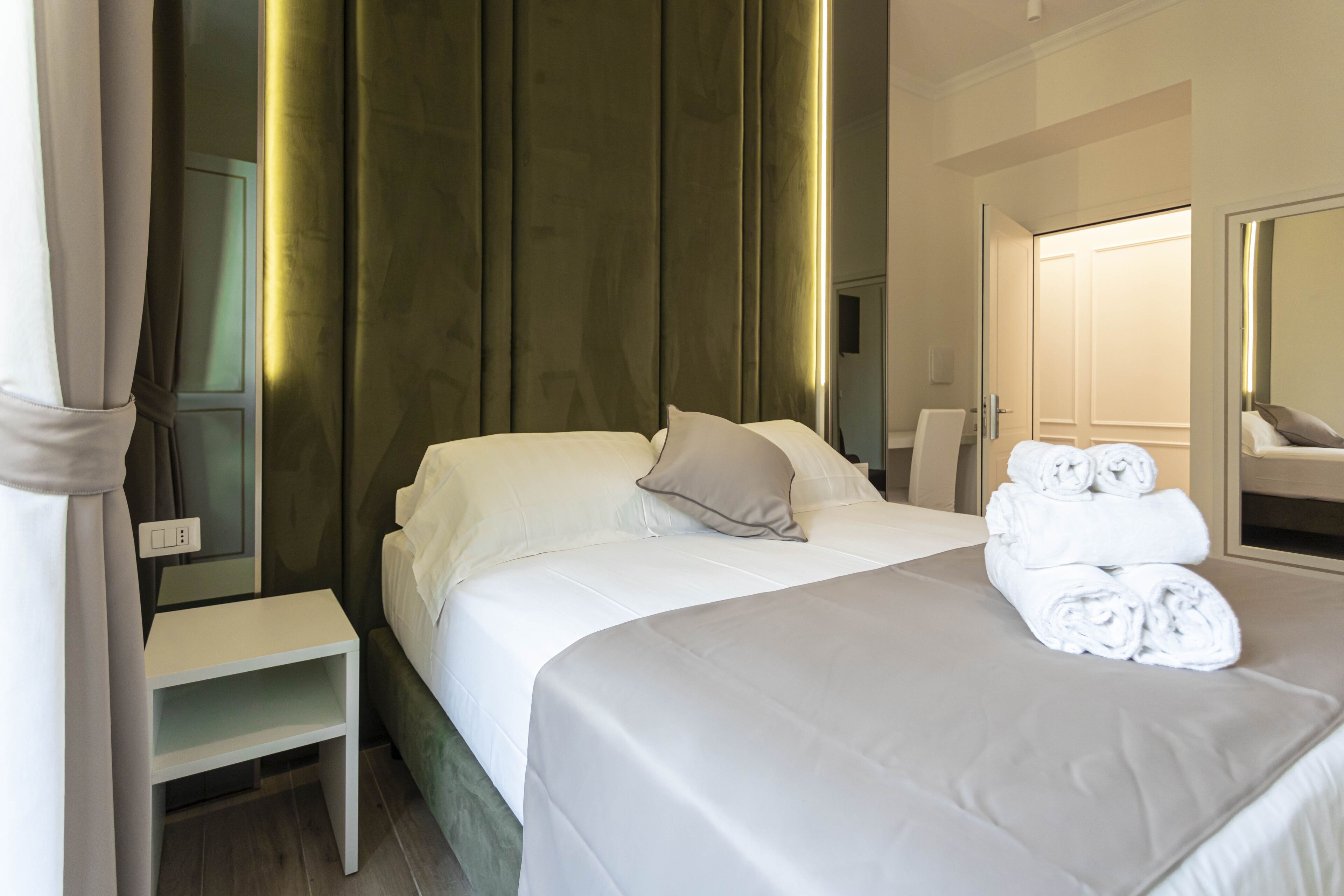 A neatly made bed with white linens and a folded towel on the side.