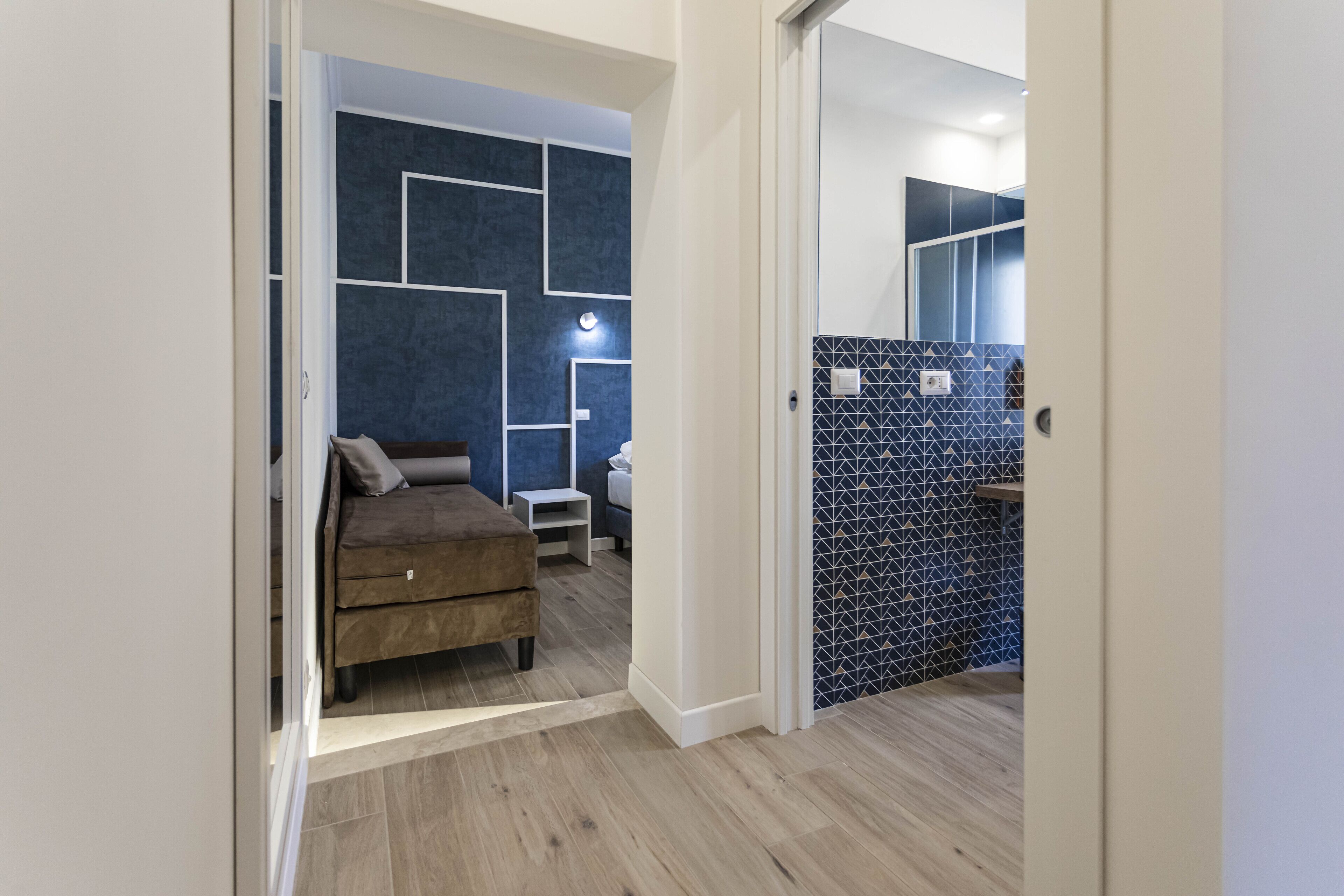 Une chambre moderne avec un lit, une table de chevet et un mur orné de motifs géométriques.
