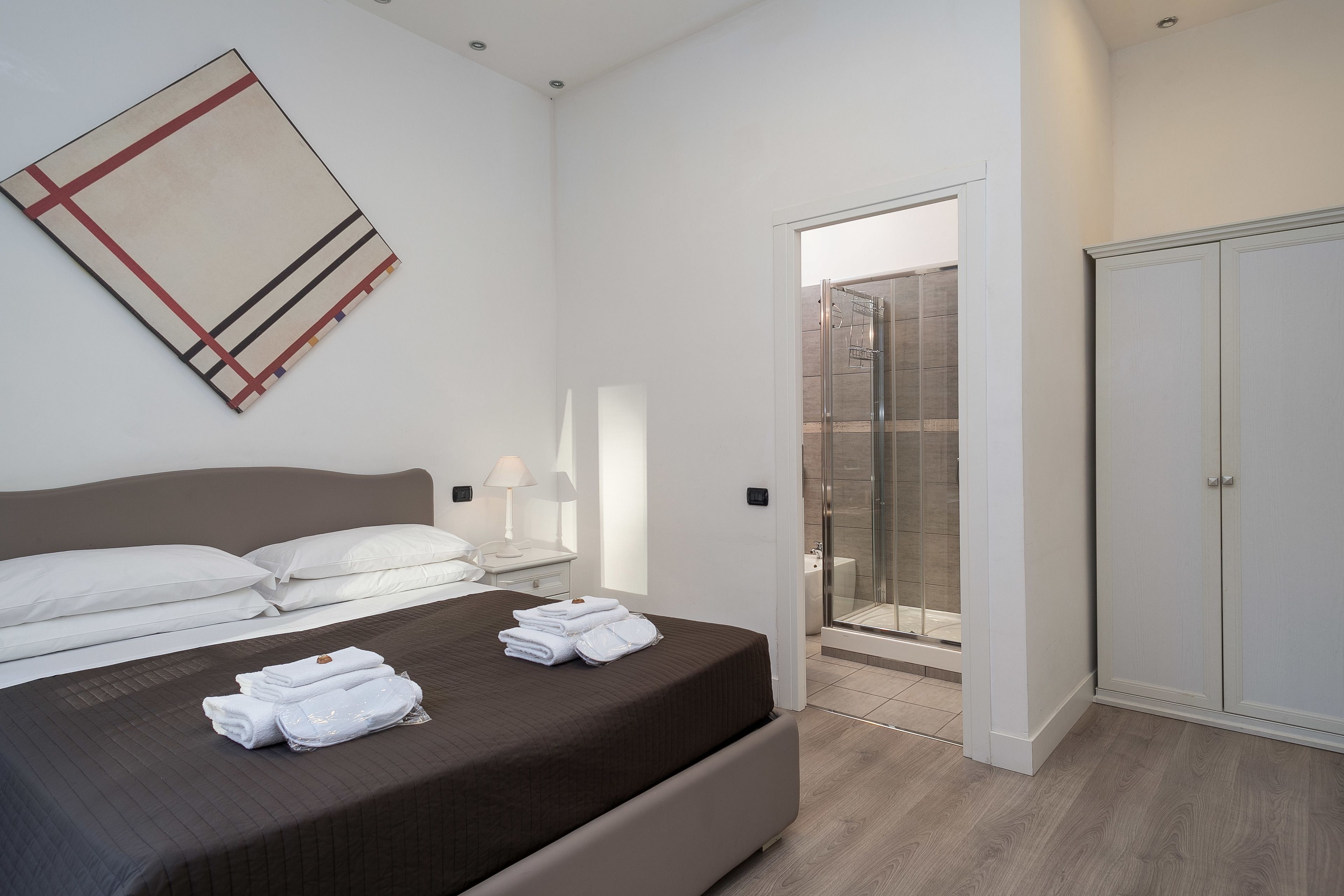 Quarto de hotel moderno com uma cama grande, chuveiro e armário.