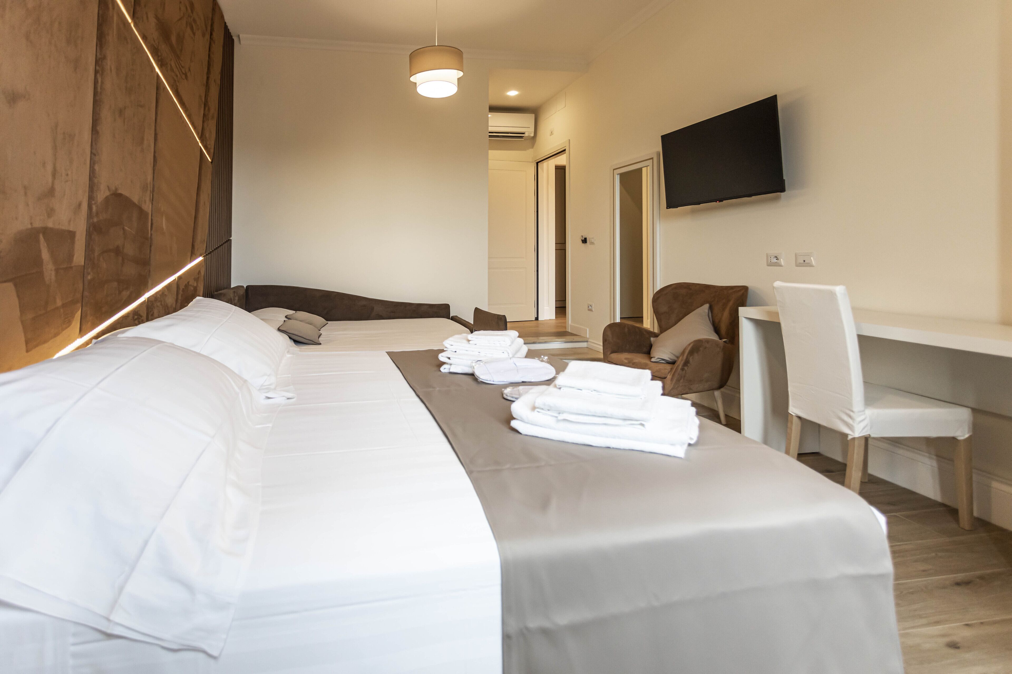 Habitación de hotel con una cama grande, un escritorio, una silla y un televisor montado en la pared.