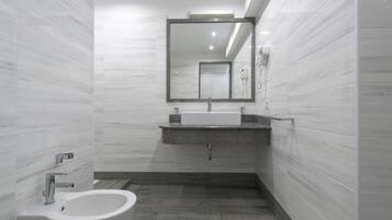 Un baño moderno con un bidé, un lavabo y un espejo.