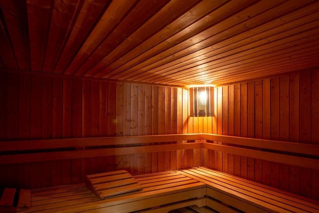 A wooden sauna with benches and a light fixture.
