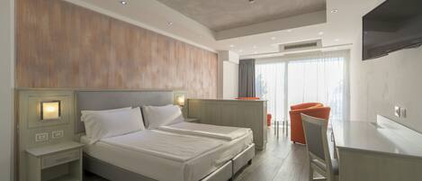 Ein modernes Hotelzimmer mit einem großen Bett, Nachttischen, einem Schreibtisch und einem Fernseher.