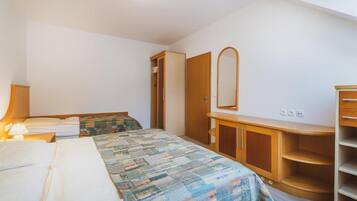 Un dormitorio con cama, armario, espejo y mesita de noche con lámpara.