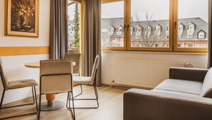Une pièce comprenant une table à manger, deux chaises, un canapé, une fenêtre avec des rideaux et un radiateur.