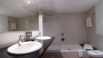 A modern bathroom with a double sink, a bathtub, and a toilet.