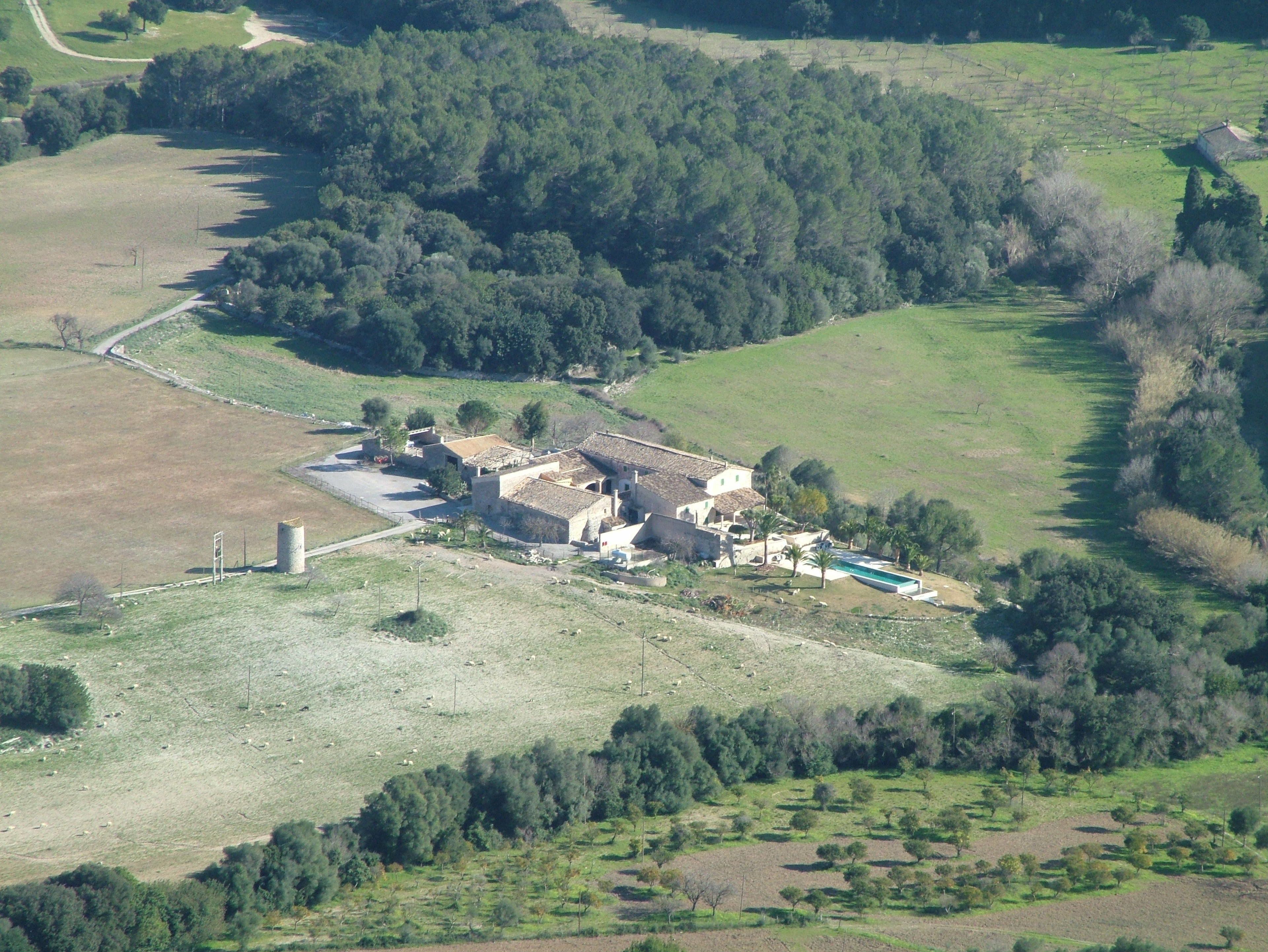 Vista aérea de una propiedad rural con una casa grande, una piscina y campos aledaños.