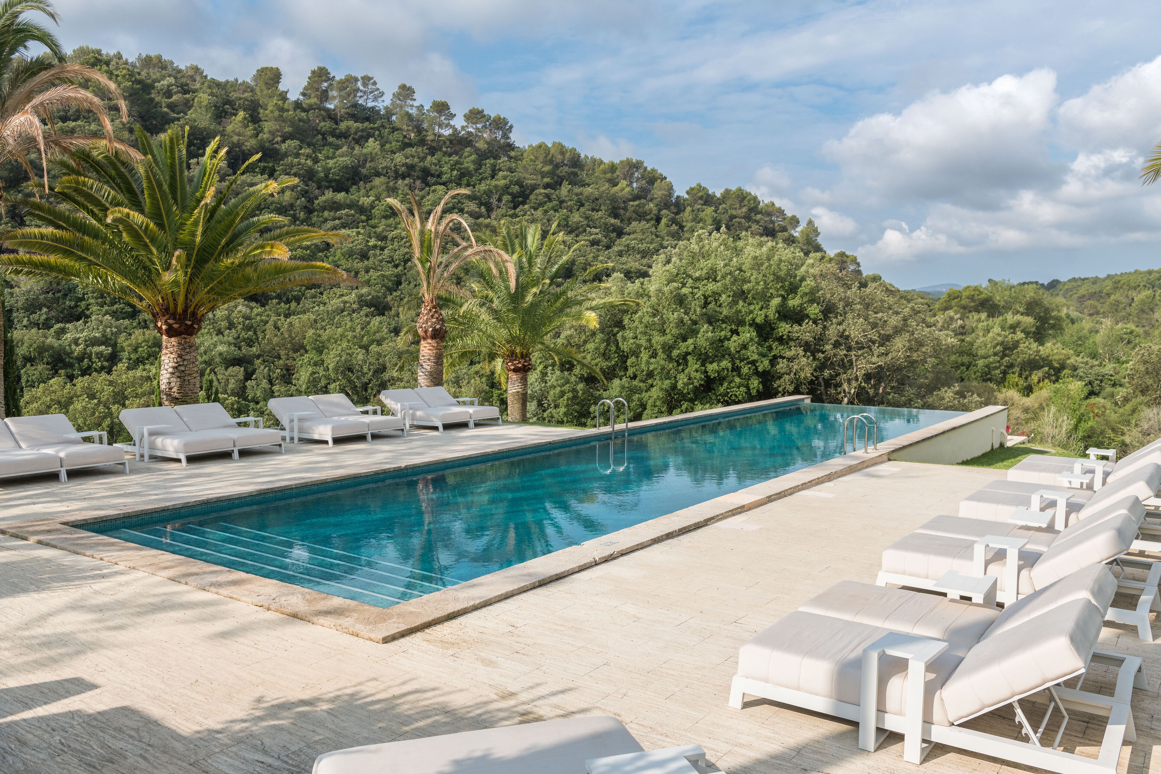 Een buitenzwembad, parasols bij het zwembad en ligstoelen