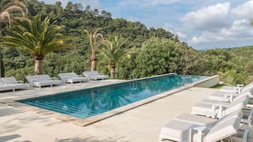 Een buitenzwembad, parasols bij het zwembad en ligstoelen