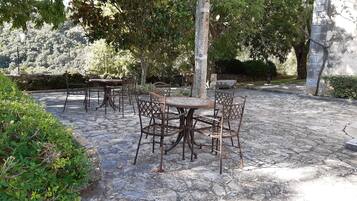 Un espace extérieur aménagé en terrasse, avec un sol en pierre, des tables et des chaises en métal.