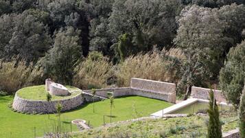 Una estructura circular de piedra con un césped, rodeada de un bosque denso.