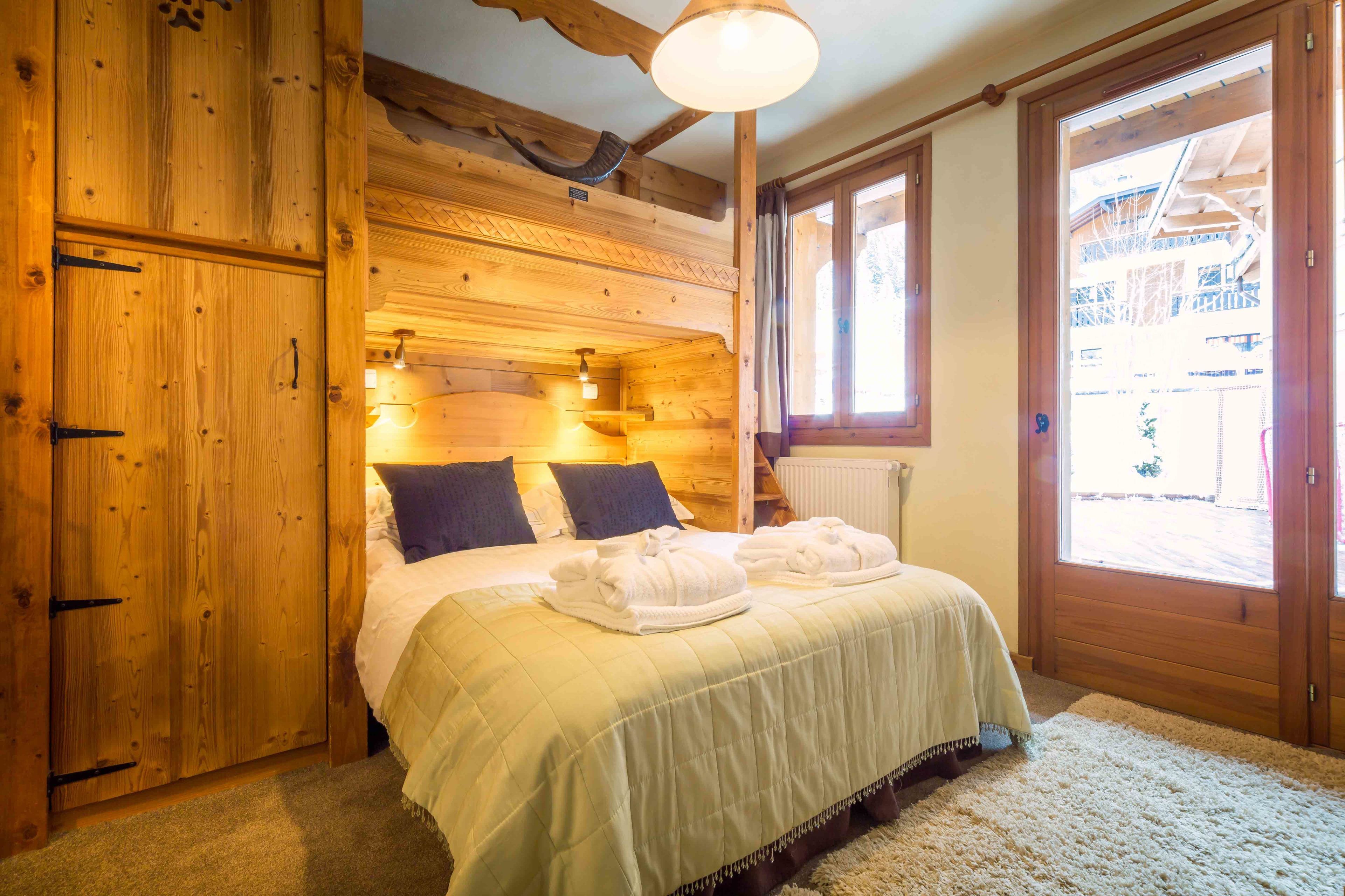Une chambre à coucher de style cabane en bois, avec un lit, deux oreillers, une table de chevet et une fenêtre.