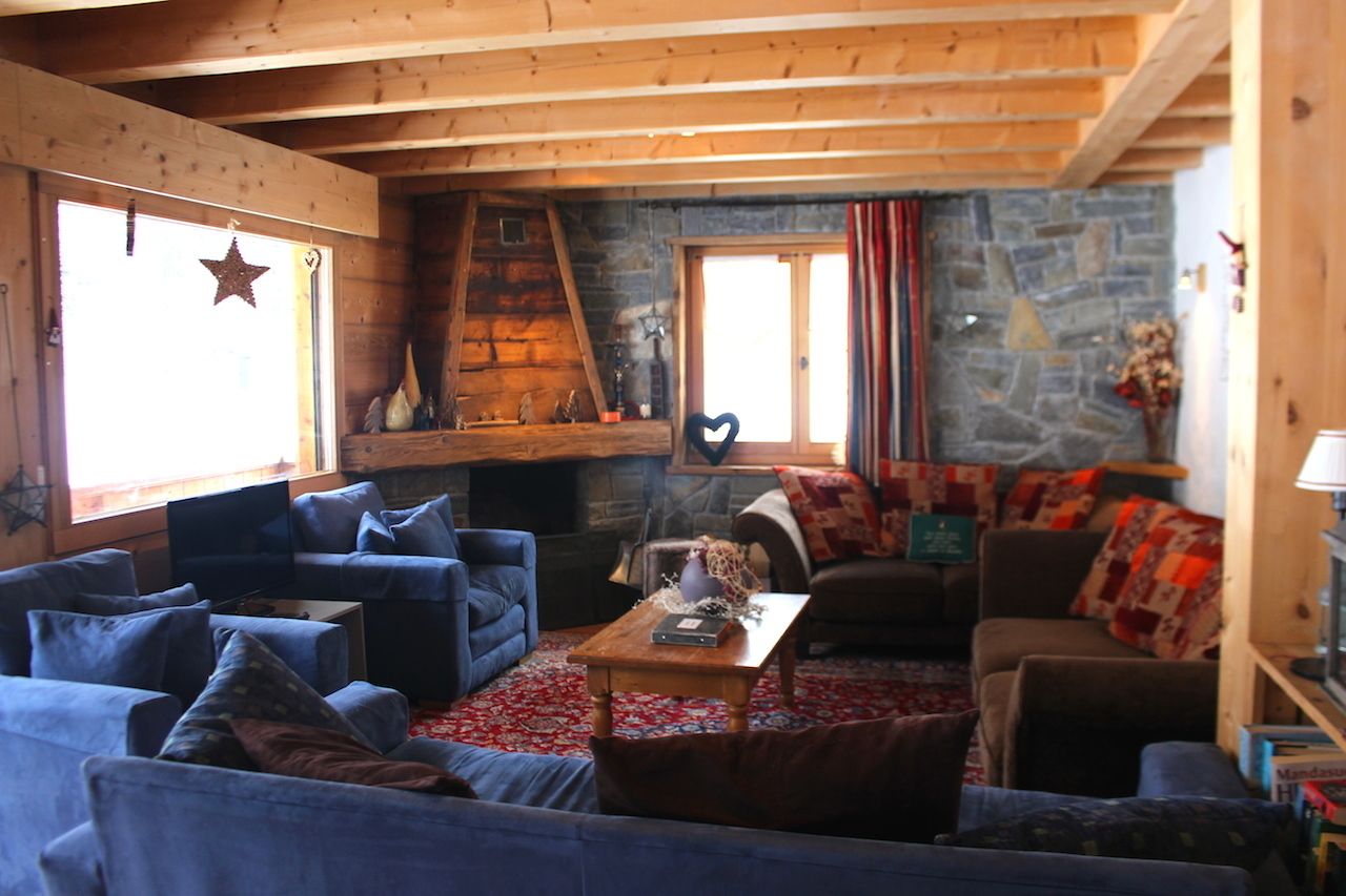 A cozy living room with blue sofas, a stone fireplace, and a wooden ceiling.