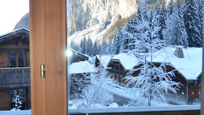 A wooden balcony with a view of snow-covered buildings and a mountain in the background. - Chilly Powder - Hôtel au Coin du Feu (Morzine)