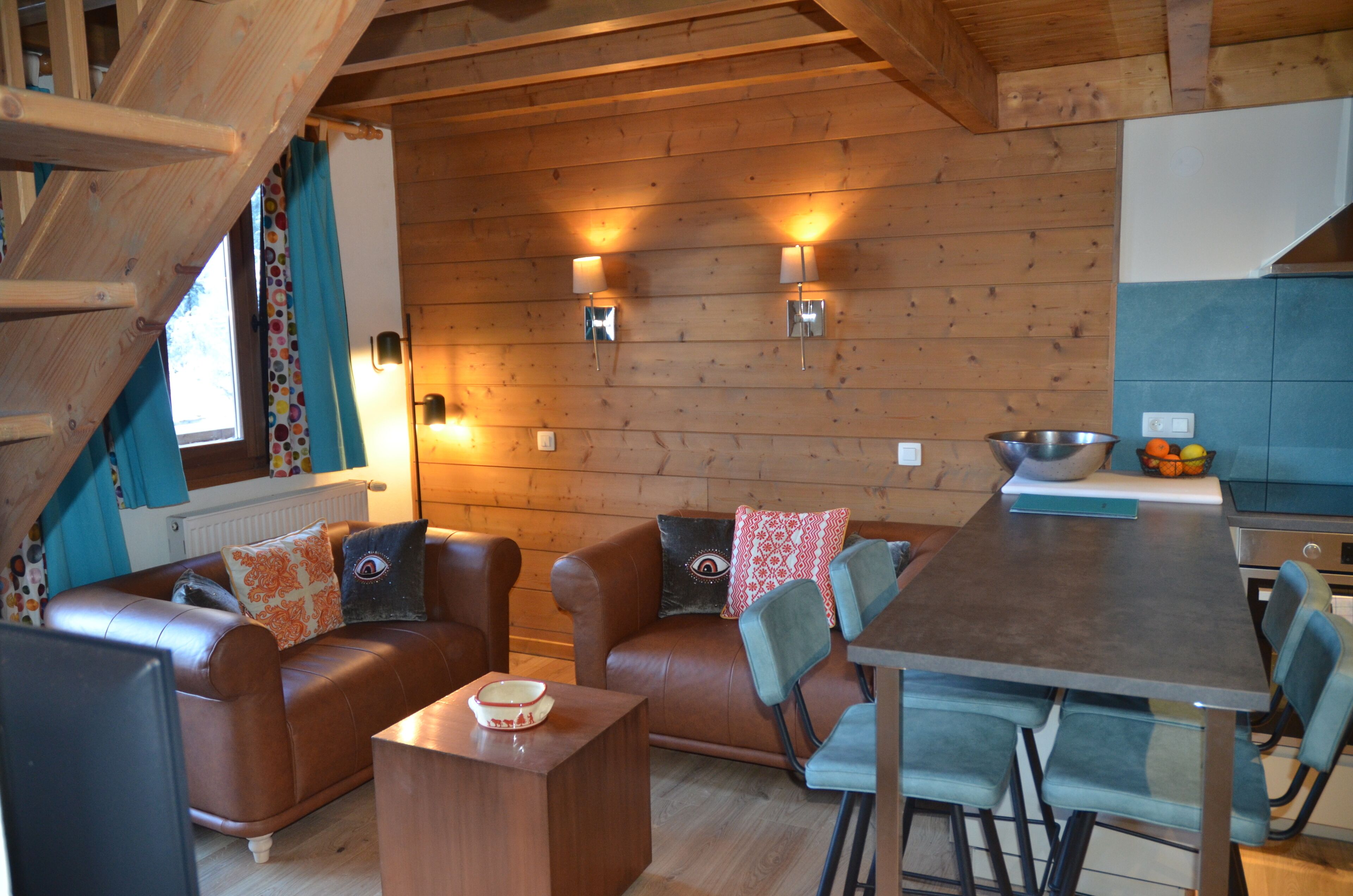 Un intérieur chaleureux en bois, avec un canapé, des fauteuils, une table à manger et un coin cuisine.