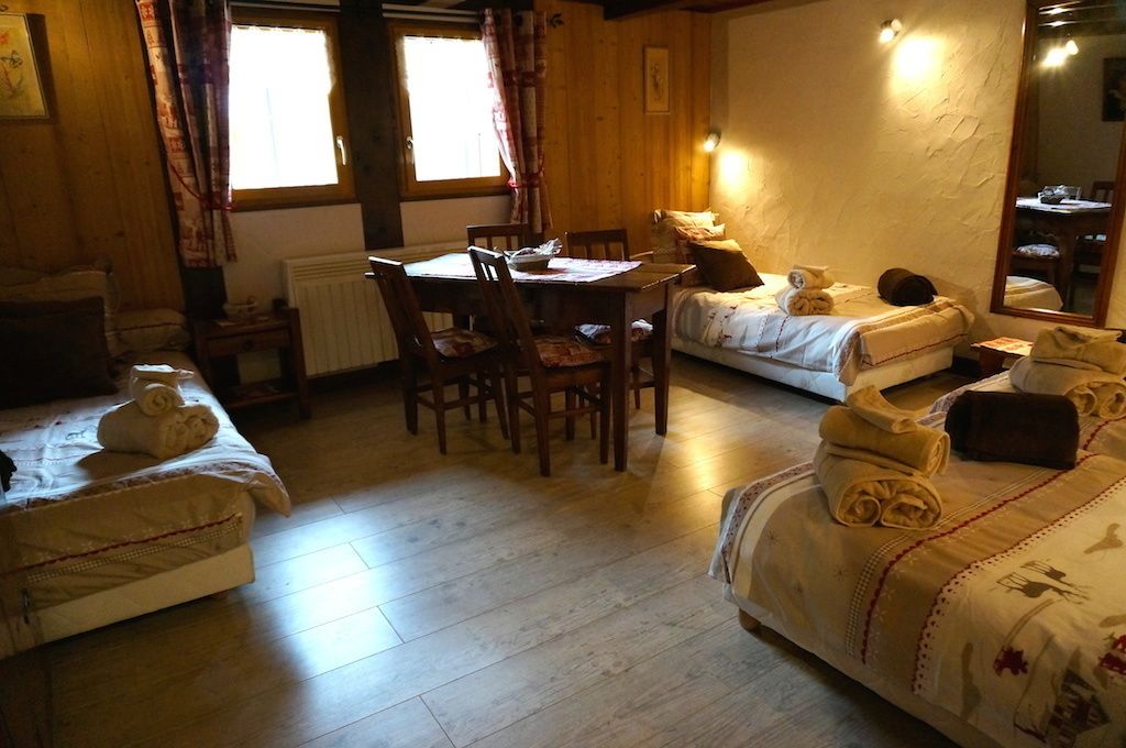 Une pièce chaleureuse avec des murs en bois, une table à manger avec des chaises, deux lits et un miroir.