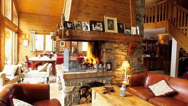 A cozy lodge interior with a stone fireplace, leather sofas, wooden beams, and a staircase. - Chilly Powder - Hôtel au Coin du Feu (Morzine)