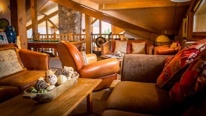 A cozy, wooden-furnished living room with leather sofas, a wooden coffee table, and a stone wall in the background. - Chilly Powder - Hôtel au Coin du Feu (Morzine)