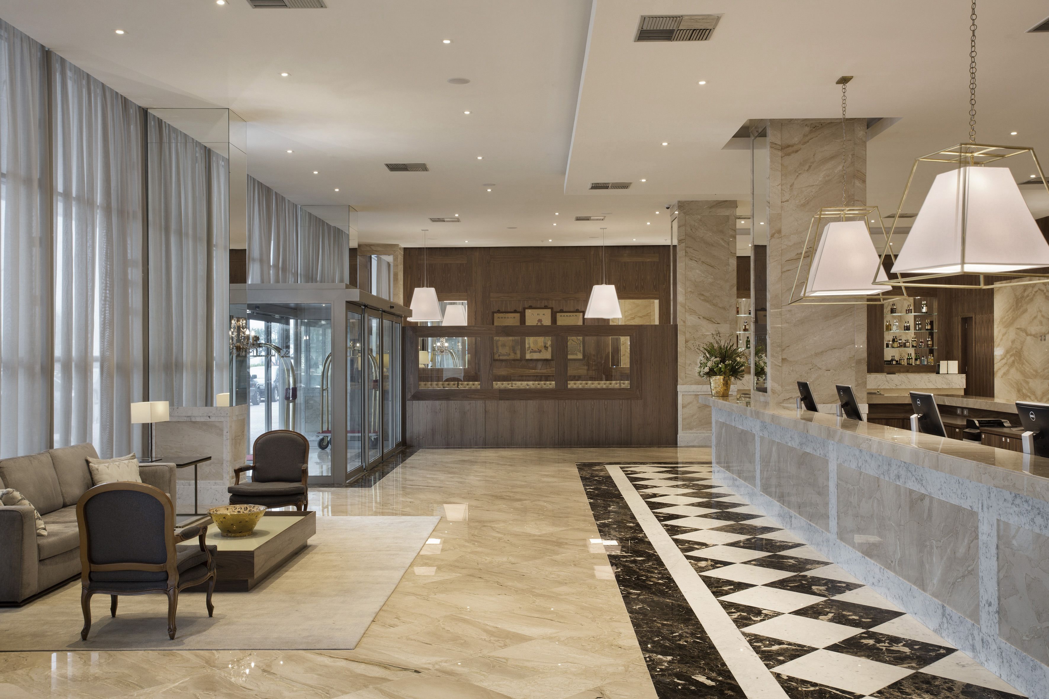 A modern lobby with a checkered floor, a reception desk, and seating area.