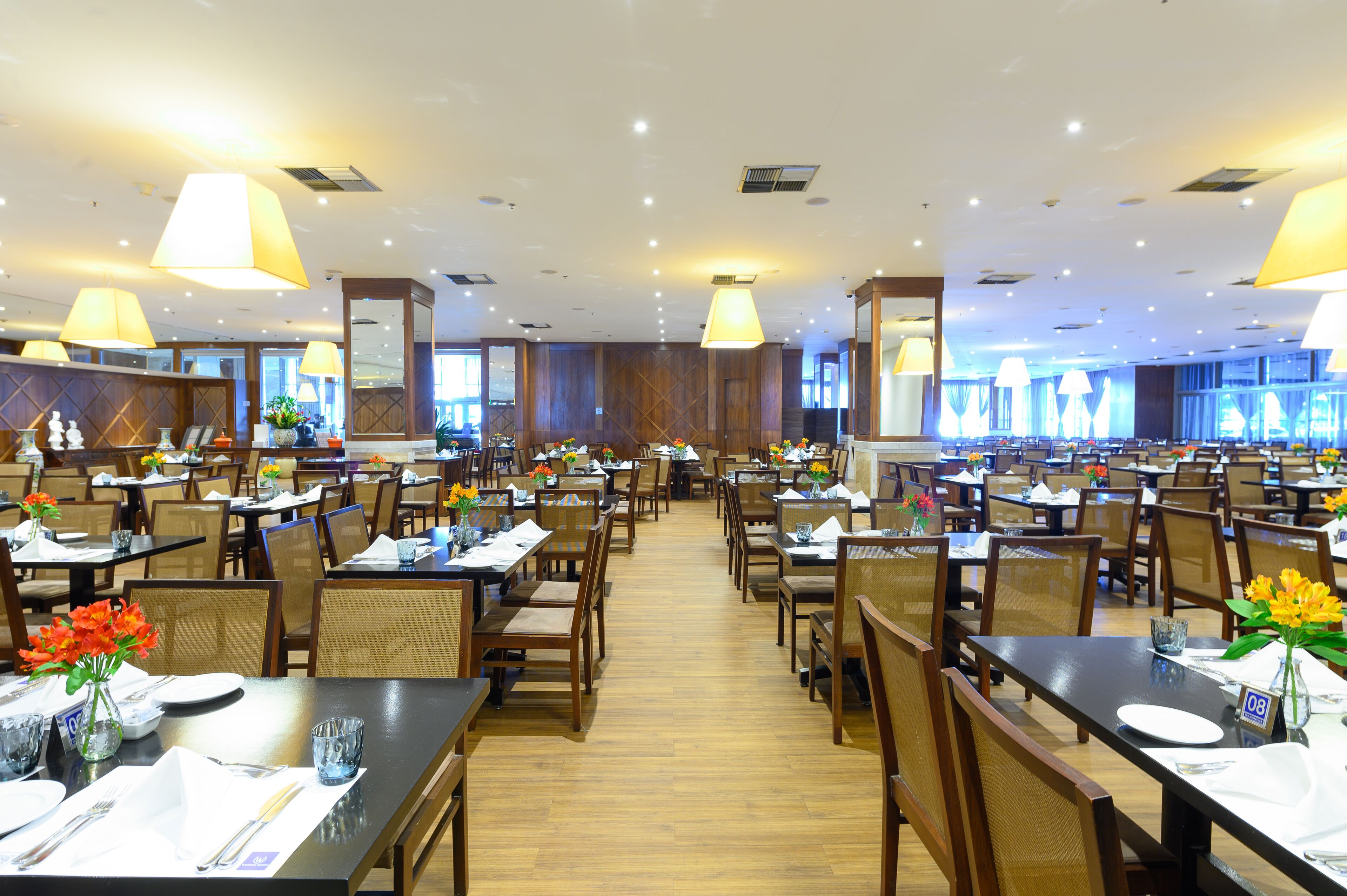A spacious restaurant with multiple dining tables and chairs, arranged in a long corridor.