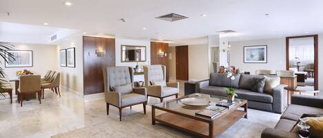 Amplia sala de estar con un sofá grande, sillones y una mesa de centro. Hay un comedor con una mesa y sillas, y una pared de acento de madera.