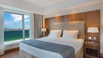 Una habitación de hotel con una cama grande, dos mesitas de noche y vista al océano.
