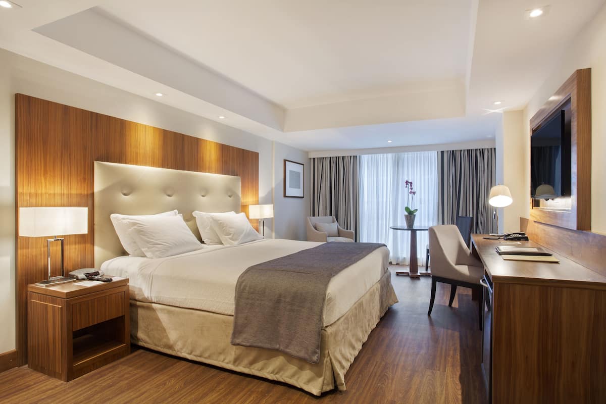 Ett hotellrum med en stor säng, sängbord, ett skrivbord och en stol.