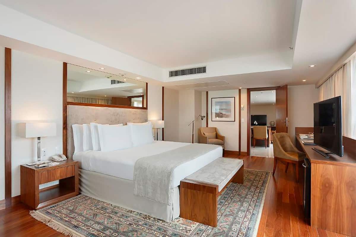 Ett modernt hotellrum med en stor säng, ett skrivbord, en tv och en spegel.