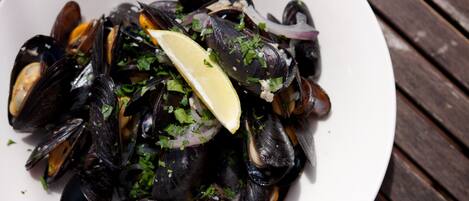 A bowl of mussels garnished with parsley and lemon.