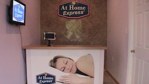 Vastaanottotiski, jossa on kyltti, jossa lukee ”At Home Express”, ja seinälle asennettu televisioruutu.