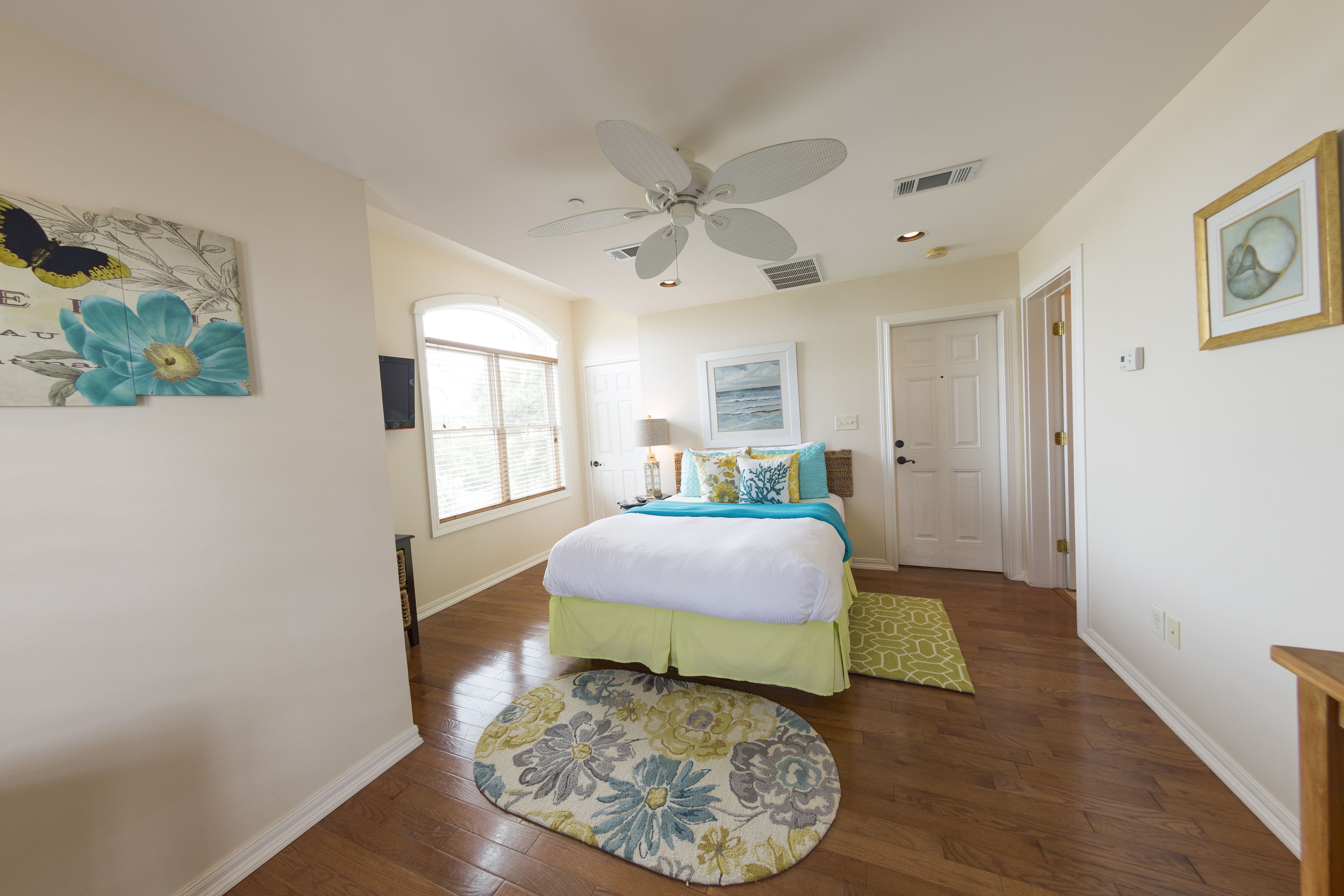 A bedroom with a bed, a ceiling fan, a window, and a door.