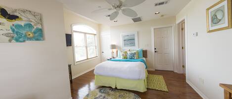 A bedroom with a bed, a ceiling fan, a window, and a door.