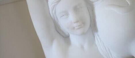Una estatua de mármol de una mujer reclinada con un brazo levantado.