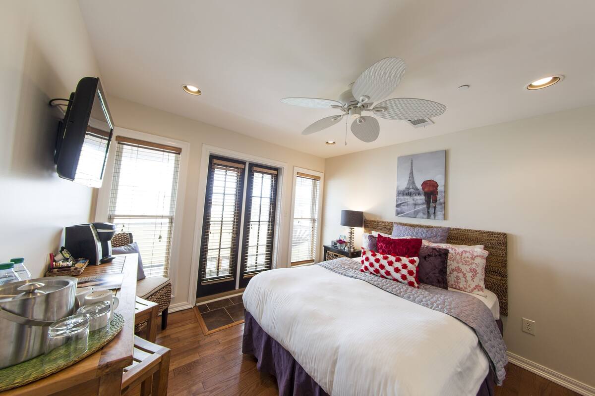 A bedroom with a bed, bedside table, lamp, and a ceiling fan.