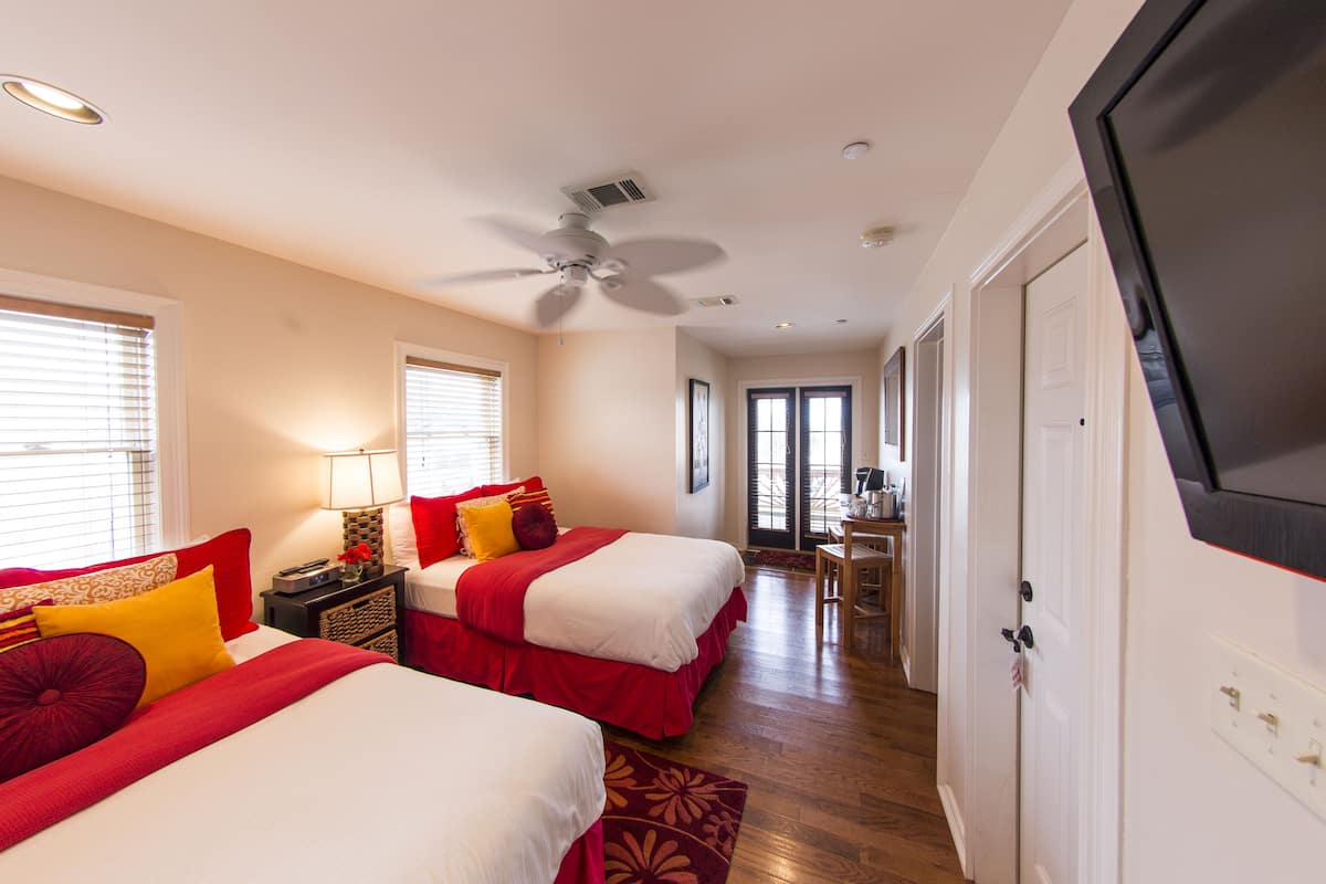 A hotel room with two beds, a ceiling fan, and a TV.