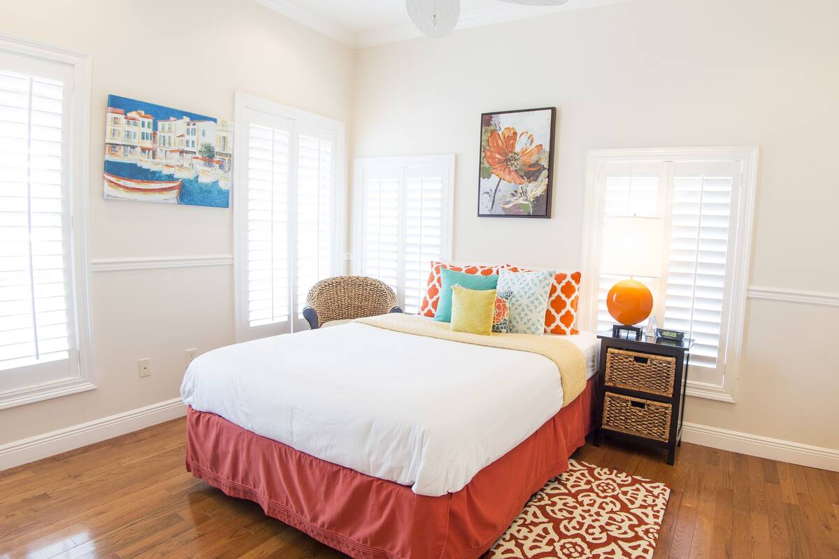 A bedroom with a large bed, a chair, a nightstand, and two wall art pieces.