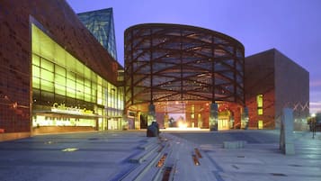 A modern building with a curved glass facade and a prominent circular structure in the center.