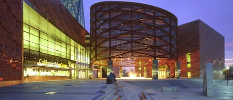 A modern building with a curved glass facade and a prominent circular structure in the center.