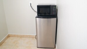 A compact kitchenette with a built-in microwave and a small refrigerator. - The Fly Inn (Lynwood)