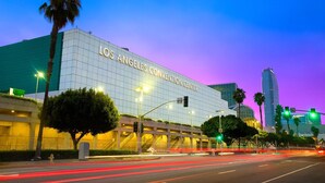 The Los Angeles Convention Center with a modern glass facade, a prominent entrance, and a parking garage in the foreground. - The Fly Inn (Lynwood)