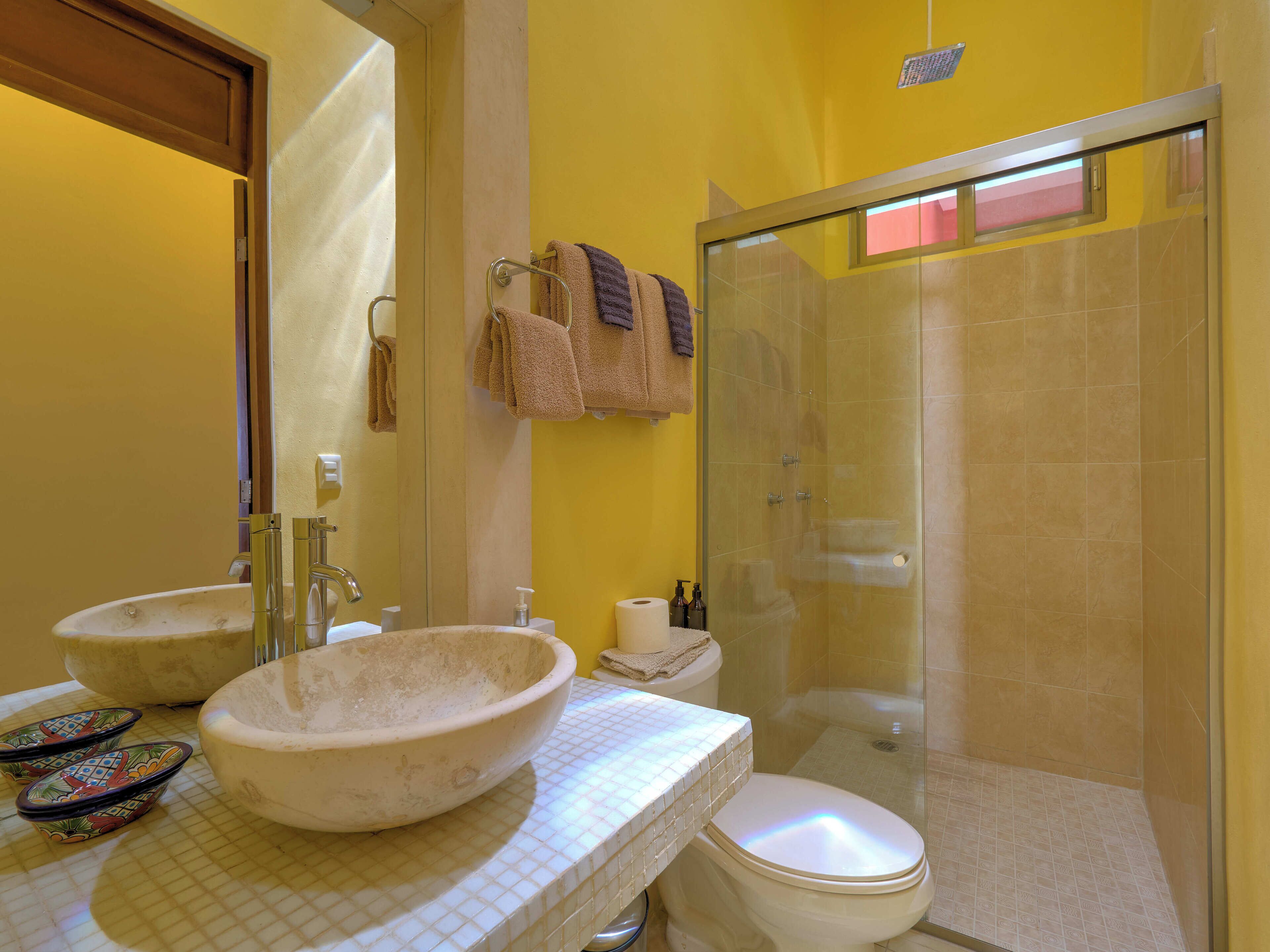 A bathroom with two sinks, a toilet, and a glass shower enclosure.