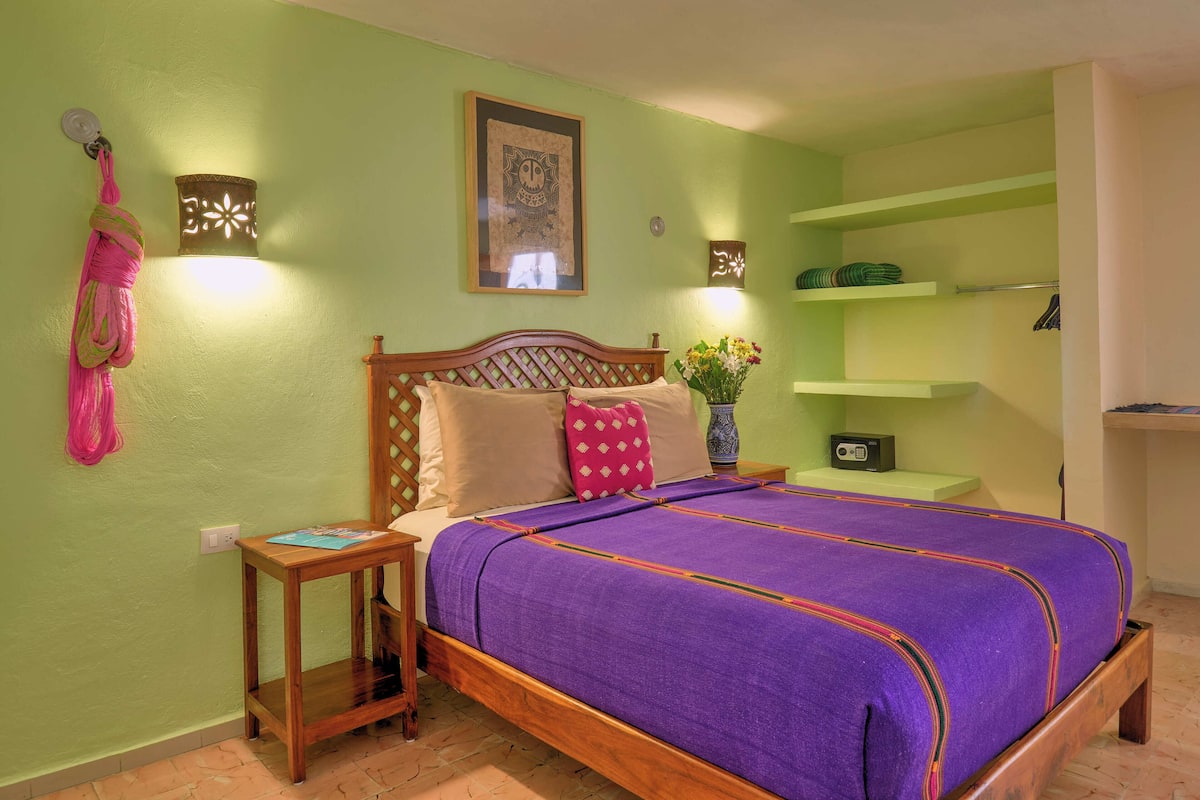 A room with a bed, a nightstand, a wall-mounted shelf, and a hanging item.