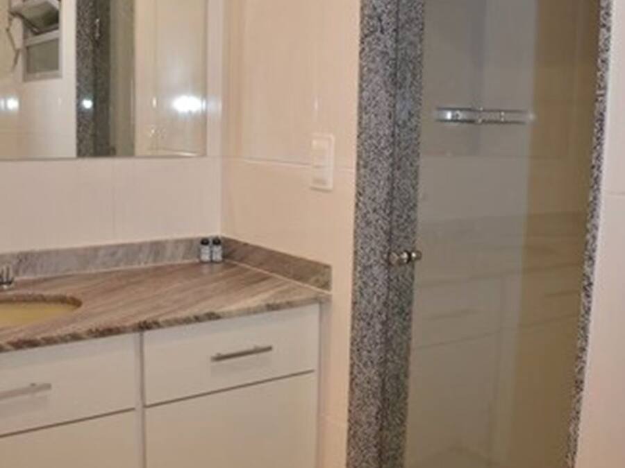 A bathroom with a shower enclosure, a sink, and a mirror.