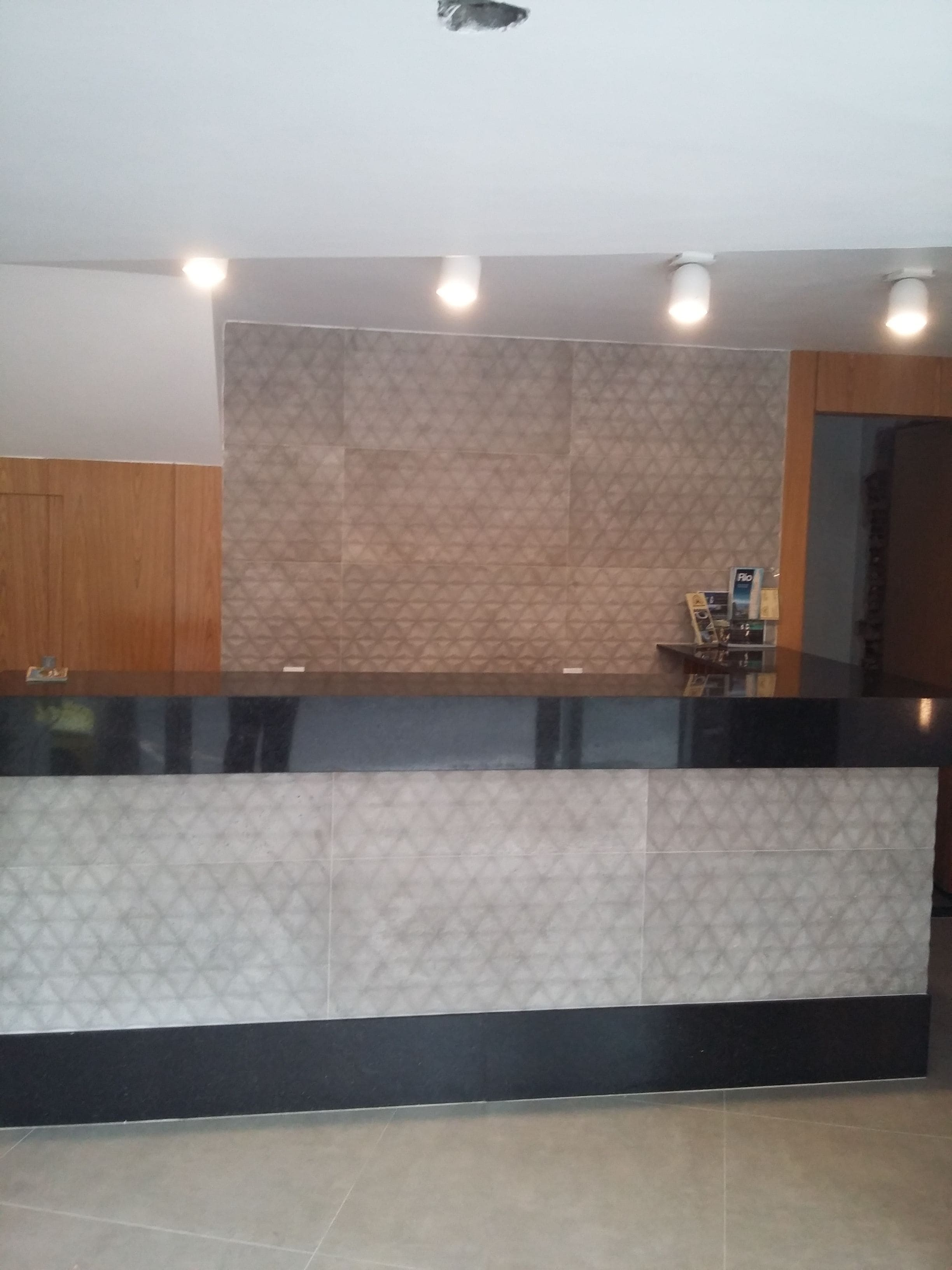 Una recepción con una pared estampada y un mueble de madera a la izquierda.