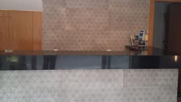 Una recepción con una pared estampada y un mueble de madera a la izquierda.