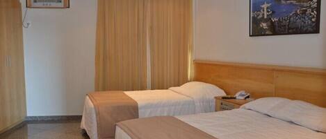 Habitación de hotel con dos camas, un cuadro en la pared y una ventana con cortinas.